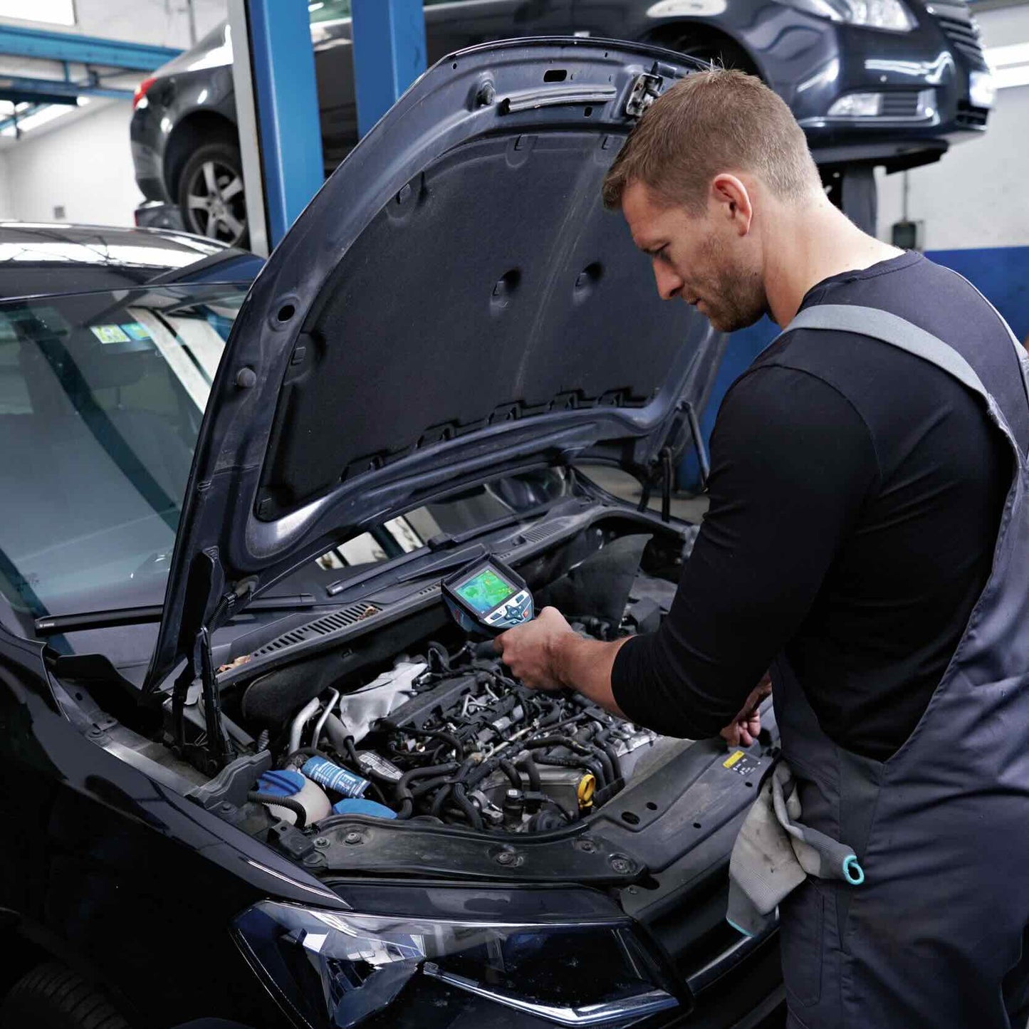 In einer KFZ-Werkstatt wird eine detaillierte Prüfung des Motorraums mit der Bosch GTC 600 C Professional Wärmebildkamera durchgeführt. Der Automechaniker erkennt auf dem Display, ob sich Motorteile stark erhitzen und ob die Motorkühlung funktioniert.